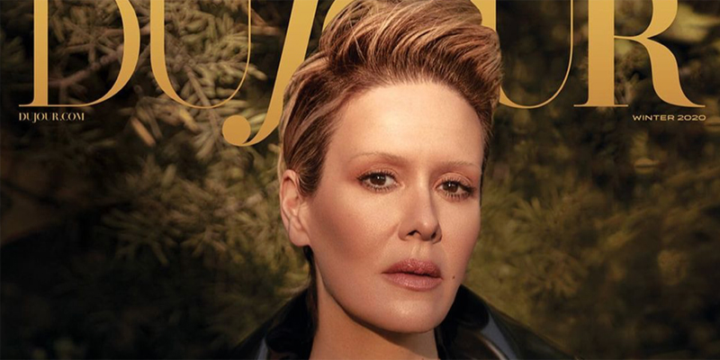 Sarah Paulson is on the cover of Dujour Magazine. Her blonde hair is slicked back and to the side. She has on neutral make up that has matted down her eyebrows, so they look invisible.