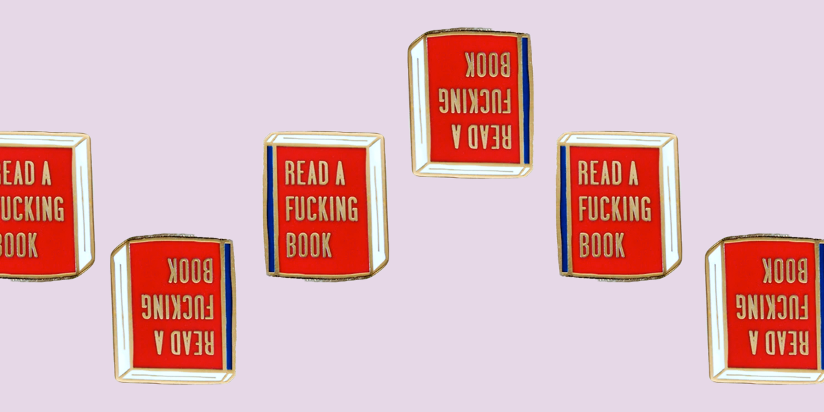 A book enamel pin with a red cover and blue spine. In gold letters the front of the book says "Read a Fucking Book".