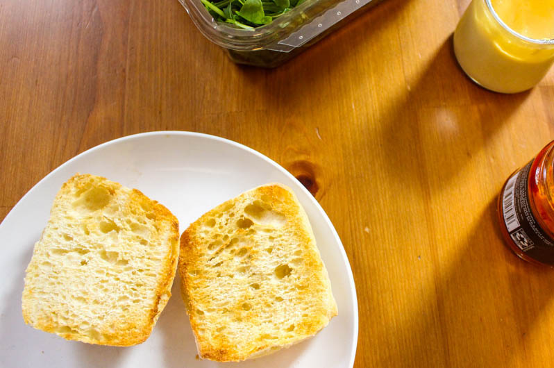 A photo of two halves of a ciabatta roll toasted on a wooden kitchen table