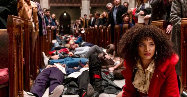 In a still from the television show Pose, Indya Moore sits on the floor of St. Peter's Cathedral during a staged "die in" during the early 1990s of HIV/AIDS Activism