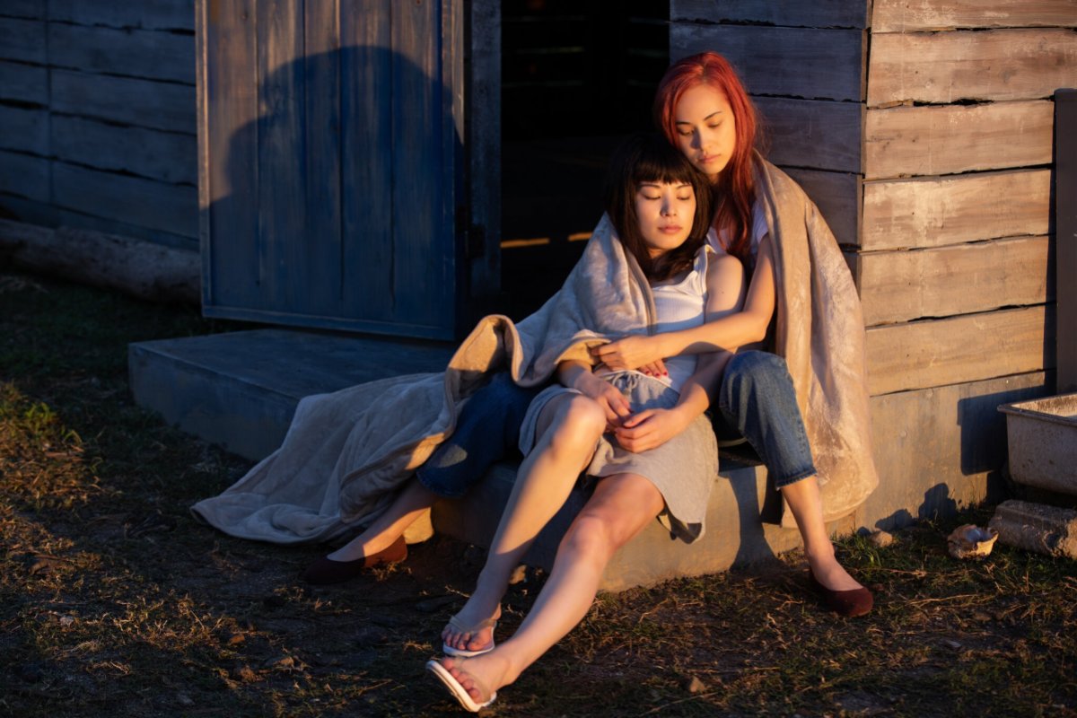 Two women holding each other sitting outside a house at sunset, still from "Ride or Die"