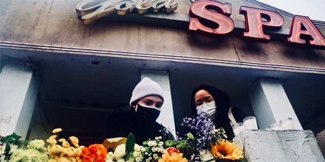 Two mourners gather in Atlanta in masks and winter coats. They leave flowers.