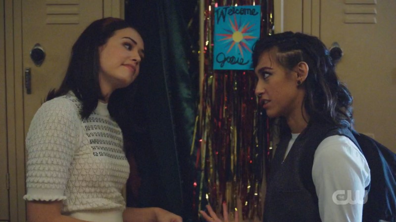 Josie and Finch exchange flirty glances in front of an open high school locker.