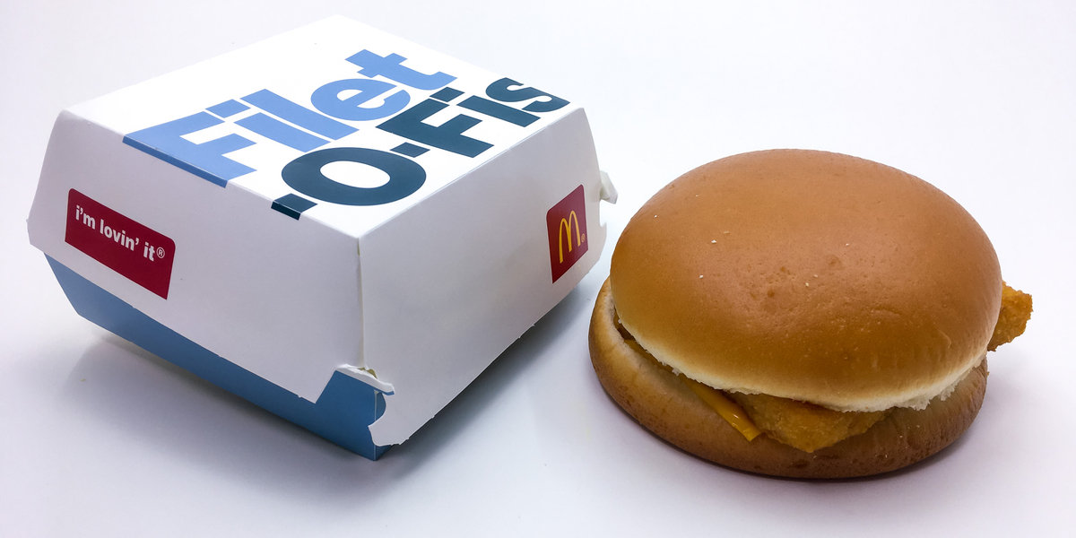 A McDonald's Filet-O-Fish sandwich sits net to a cardboard sandwich box.
