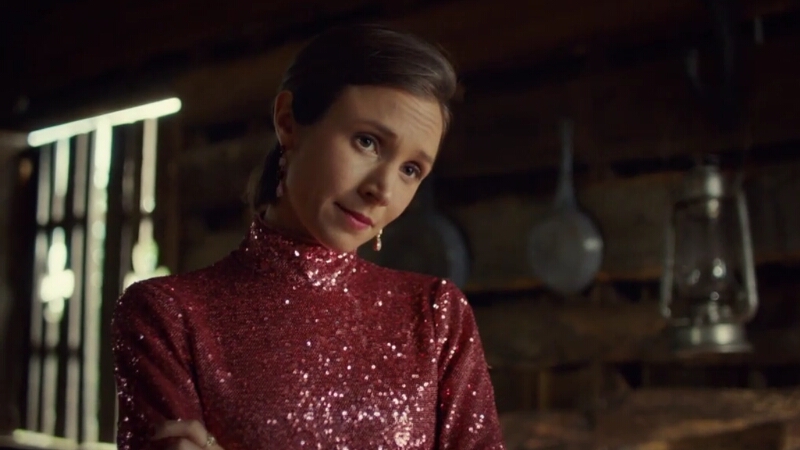 Waverly, wearing a pink glittery mock turtleneck, tilts her head as she regards off-screen Wynonna with a loving but worried look. 