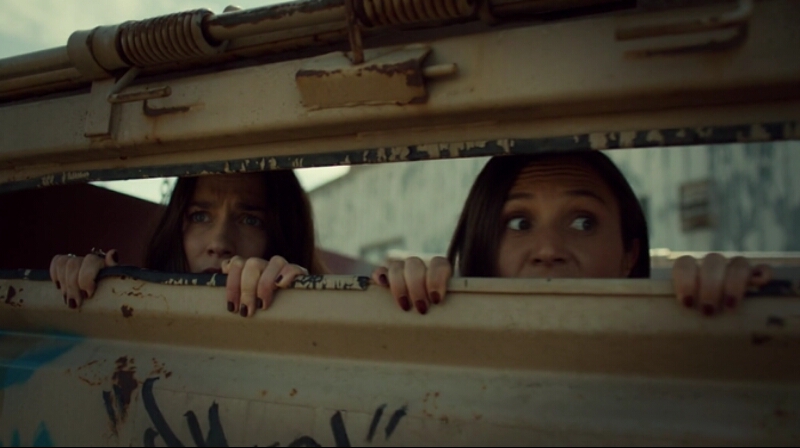 Wynonna and Waverly peek just their eyes out of the dumpster they're hiding in.