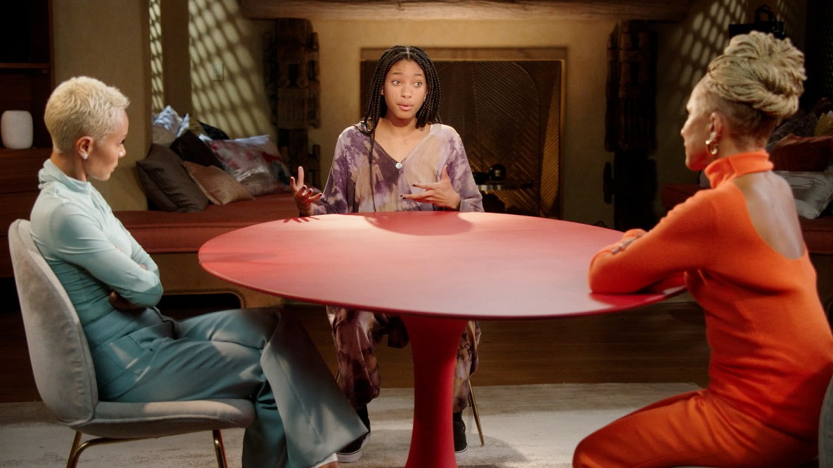 Image shows 3 Black people (Gammy, Jada Pinkett Smith and Willow Smith) sitting around the infamous Red circle table in what looks to be a living room.