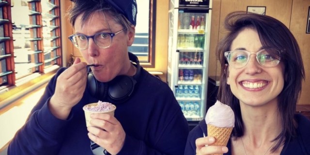 Hannah Gadsby got married in January, and this is her wife Jenney. They are eating ice cream together inside on a sunny day against wood paneled walls.