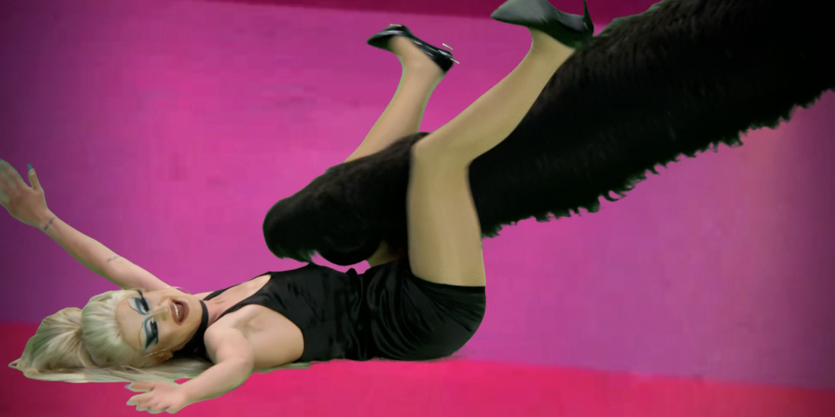 Rupaul's drag race recap: Gottmik is in a little black dress lies on her back as a giant cat paw attacks her between her legs