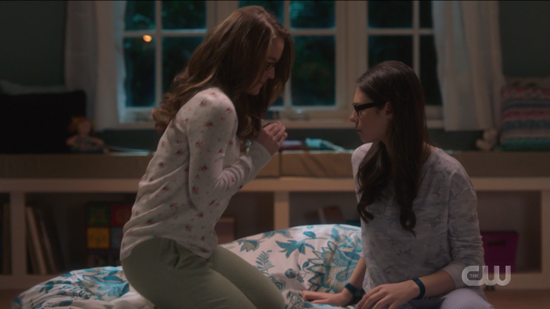 Kara shows Nia her necklace. They're both in PJs! It's very cute.