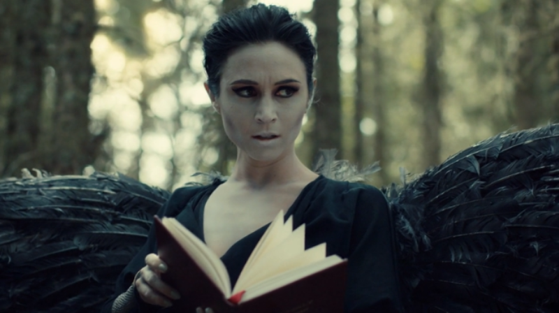 Dark Angel Waverly holds a book.
