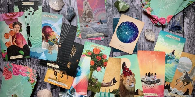 Dozens of colorful tarot cards scattered all over a wooden surface