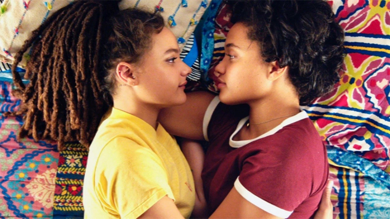 Good First Date Movies for Lesbians: Kiersey Clemons and Sasha Lane lie in bed facing each other