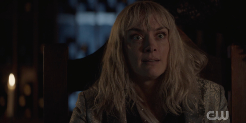 Alice's eyes are wide in a candelit room
