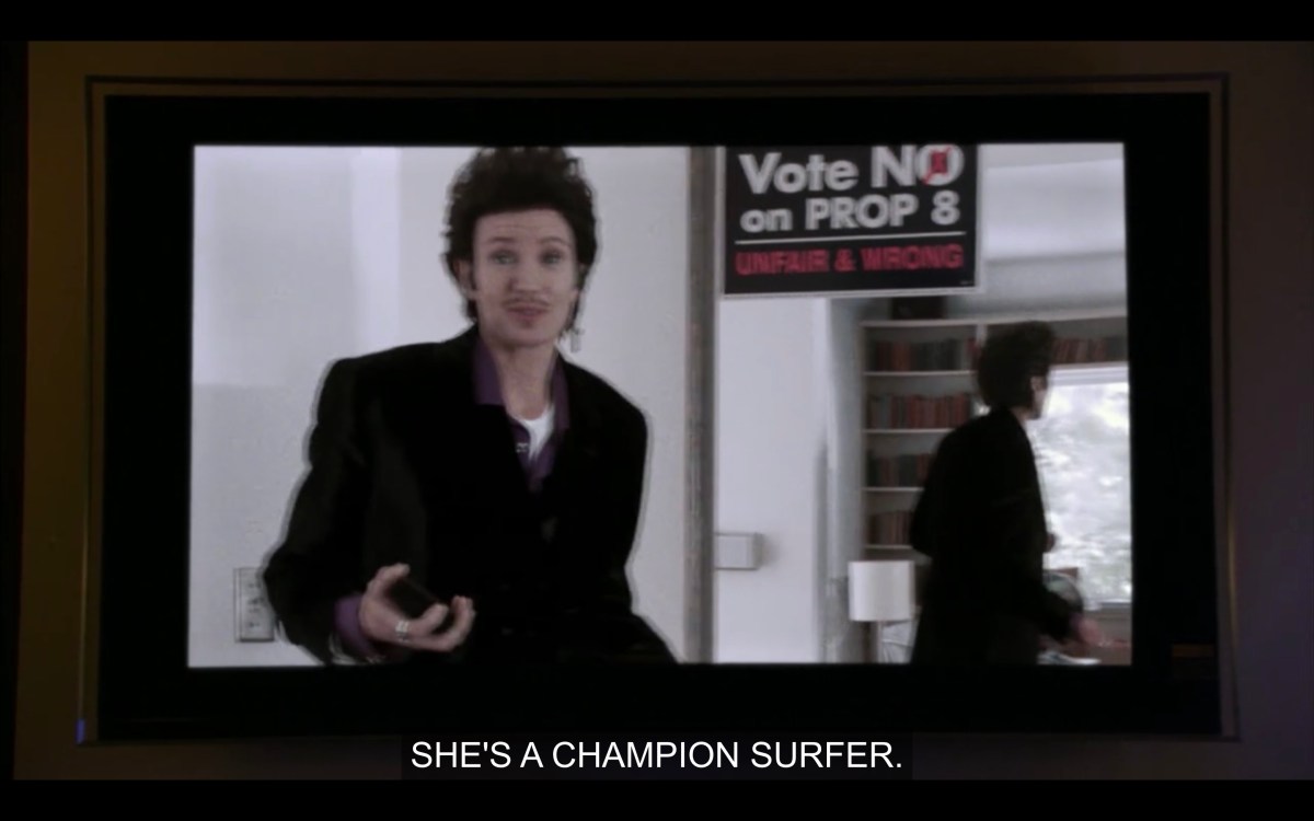 Ivan in front of his mirror that has a "Vote No on Prop 8" poster on it, in the Bette + Tina tribute video