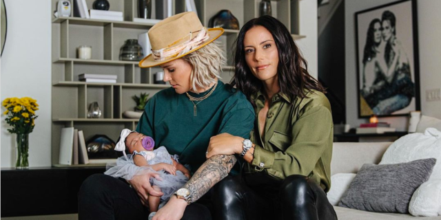 A screenshot of a mother's day Instagram post in which Ali Krieger and Ashlyn Harris are cradling their baby on a sofa.