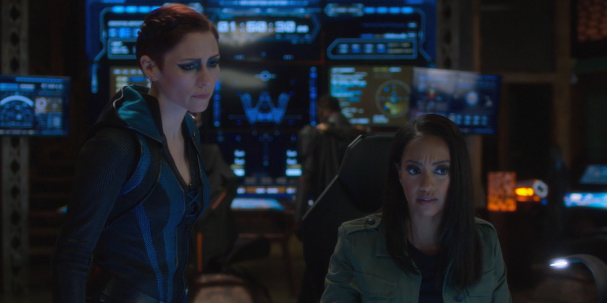 Screenshot from Supergirl: Alex and Kelly look down at the spaceship's interface.