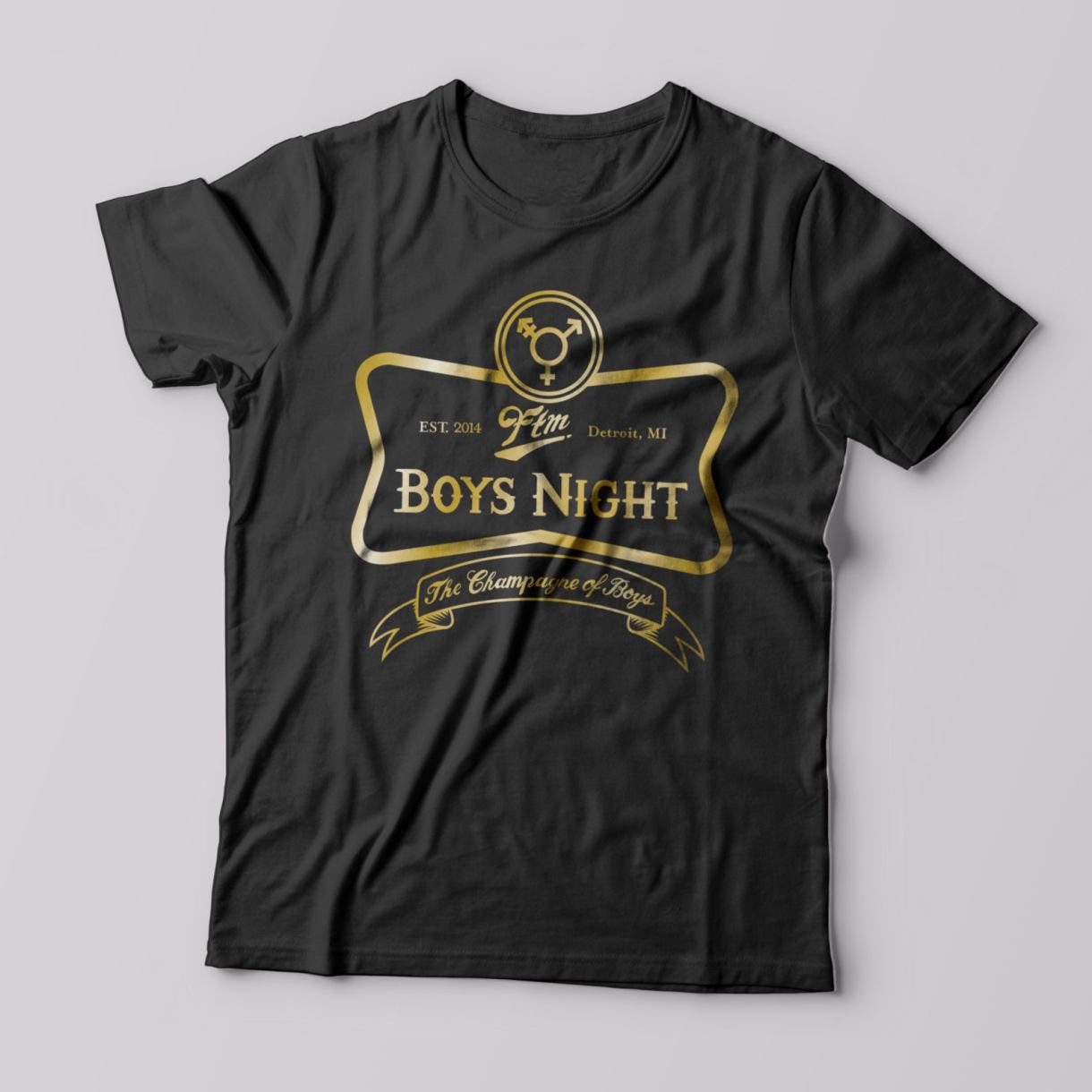 Black t-shirt with a gold logo that says "FTM Boy's Night". In a circle atop the frame there is a trans symbol. A ribbon beneath says 'the champagne of boys." Similar to a beer/bar label.