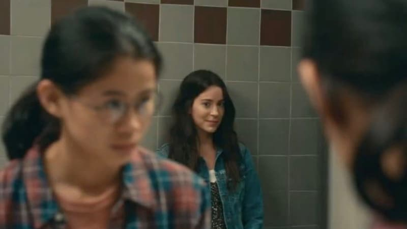 Aster shares a knowing look with Ellie in the bathroom mirror