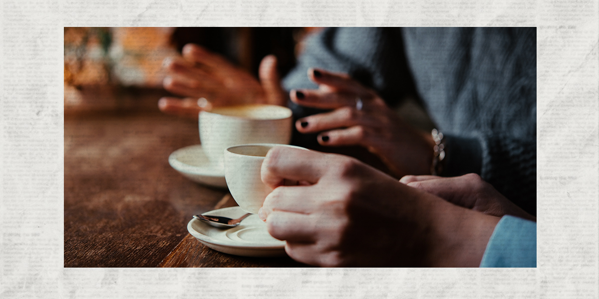 A photo of two women's hands holding coffee and gesturing at a brunch table laid over a newsprint background