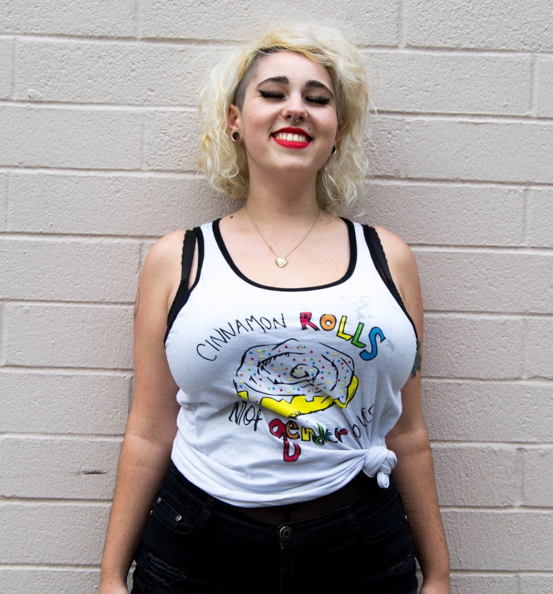 Model wearing a tank top with a sketch of a dripping cinnamon roll and the words "Cinnamon Rolls not Gender Roles" encirling it