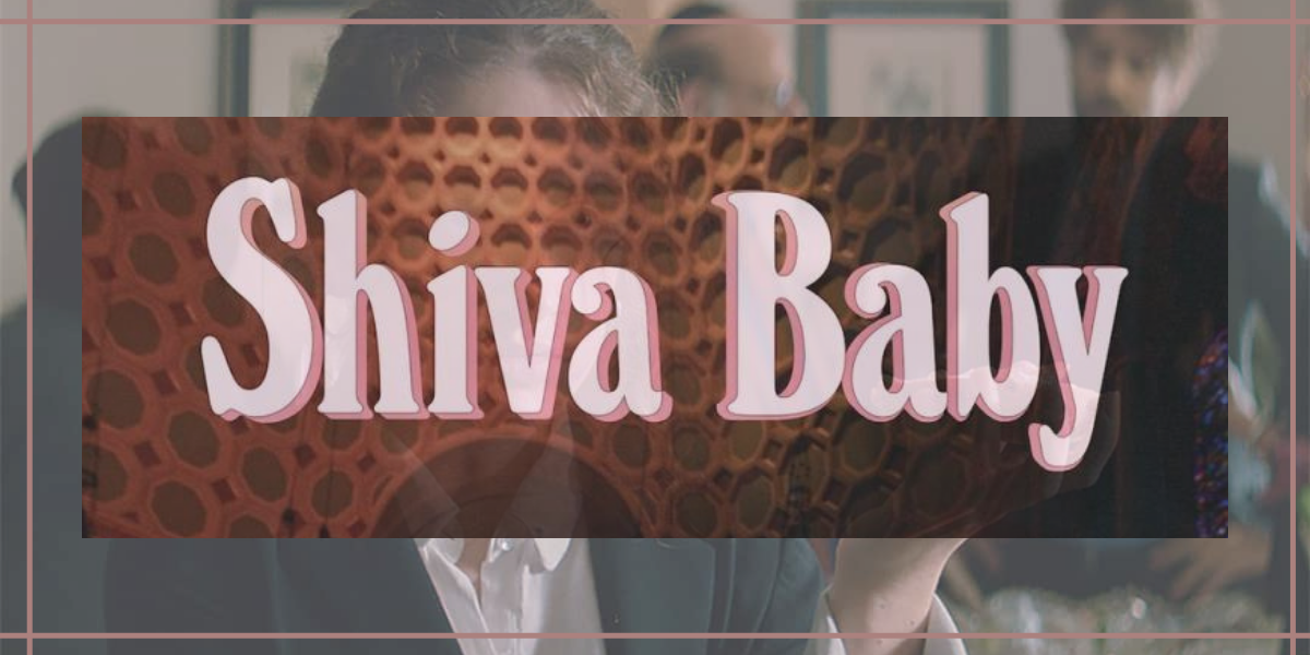 Image shows pink text that reads "Shiva Baby" overlaid on an image of a woman in a black and white suit holding a bagel smeared in cream cheese and smoked meats.