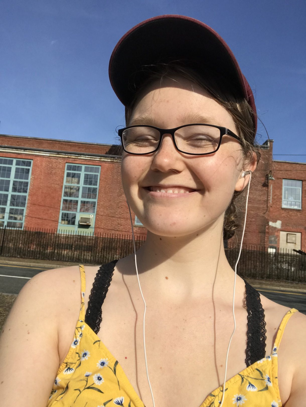 Ann wearing headphones and a baseball hat outside