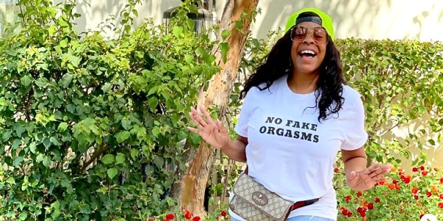 Niecy Nash has on a shirt that says "No Fake Orgasms" while smiling into the camera