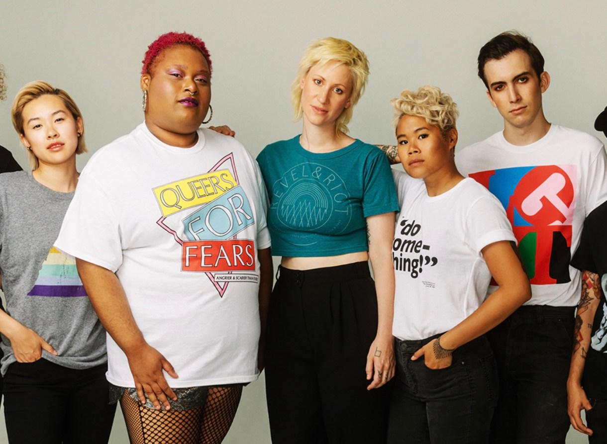 Models in Revel + Riot tees: a grey shirt with a triangle rainbow, a white shirt with "QUEERS FOR FEARS" in yellow, blue and red blocks, a dark teal Revel + Riot shirt, a "Do something!" shirt and an LGBT art shirt.