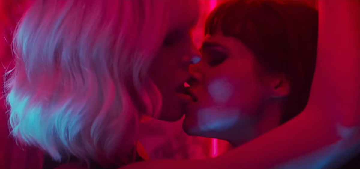 Charlize Theron kisses a woman against a wall in dark pink neon lighting