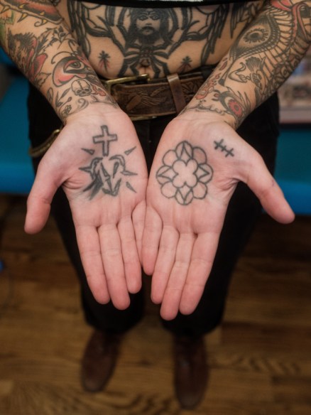 Image shows the tattooed palms of Sema. Their hands are together and opened with palms facing upward.