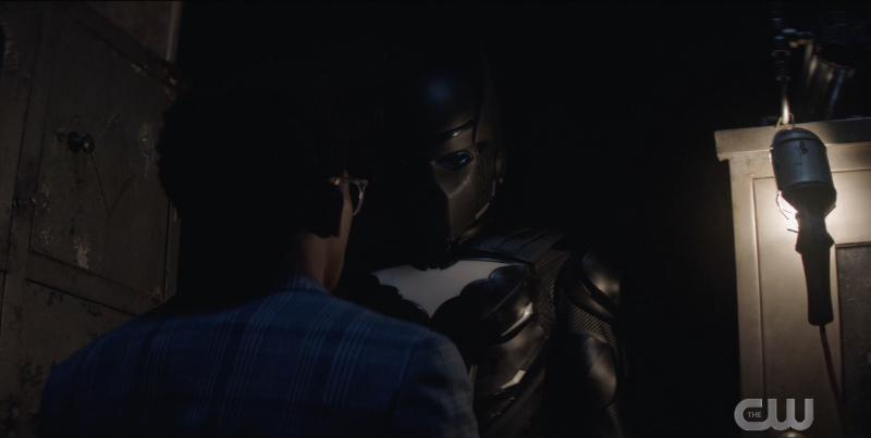 Batwoman season 2 finale recap: Luke stands in front of the Batwing suit: Black armor with a light blue Bat emblem on the chest