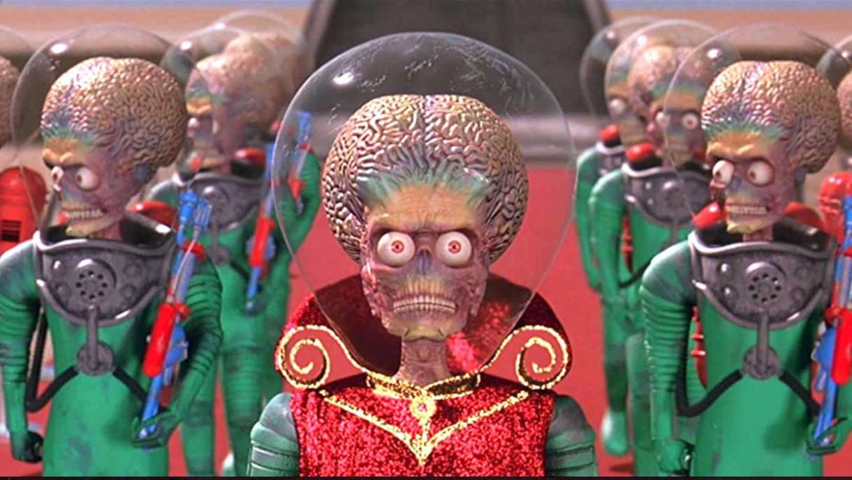 A group of martians from the film Mars Attacks dressed in bright red and green clothes with glass domes over their giant craniums