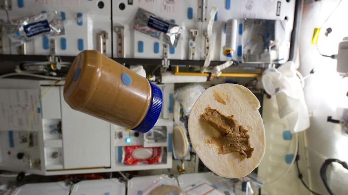 A jar of peanut butter floats towards a flour tortilla in zero gravity on a space shuttle