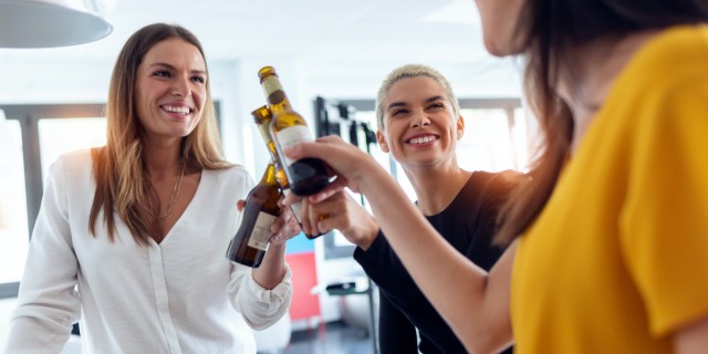 Shot of three young entrepreneur women toasting with a bottle of beer to celebrate a success in the office.