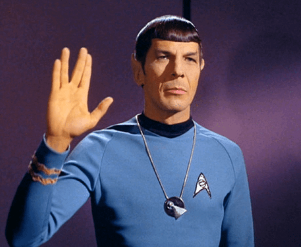 Spock from Star Trek in his blue uniform making the classic Vulcan hand sign