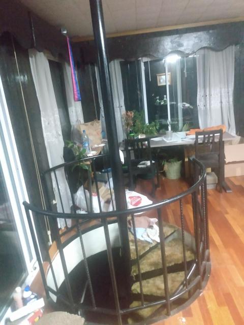 a room with a spiral staircase and a desk in the corner, lots of windows