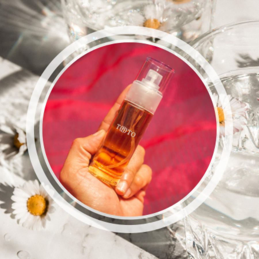 Image shows someone holding a bottle of the TOTO lube overlaid on an image of daisies in water glasses.