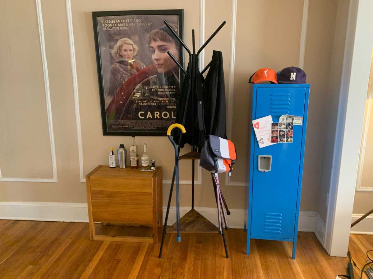 Living room wall with bright blue storage locker, small bar, and a coat rack with blue and yellow cane leaning up against it