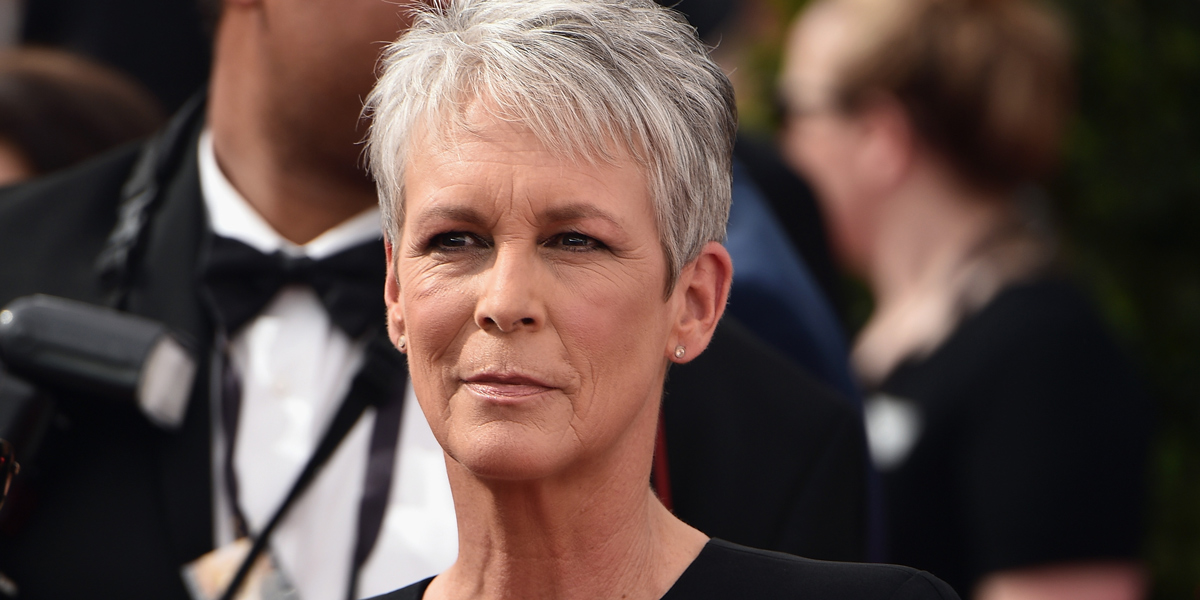 A silver haired Jamie Lee Curtis looks intensely into the camera with a black dress on.