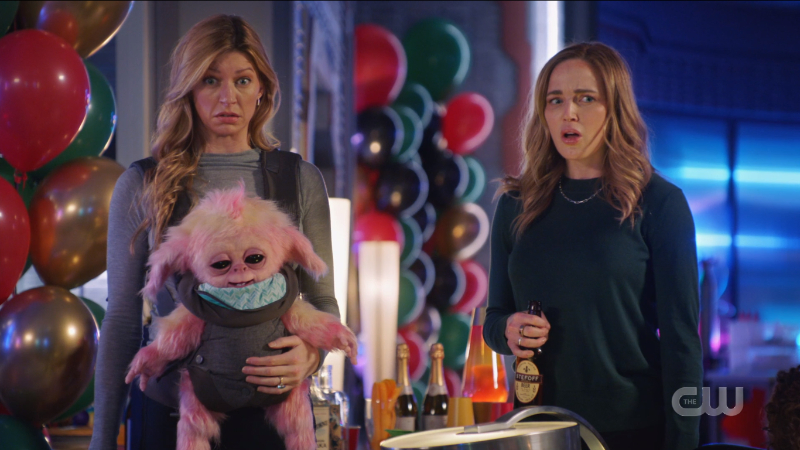 Legends of Tomorrow Episode 609: Avalance, Sara and Ava, at a birthday party looking surprised and holding a baby alien