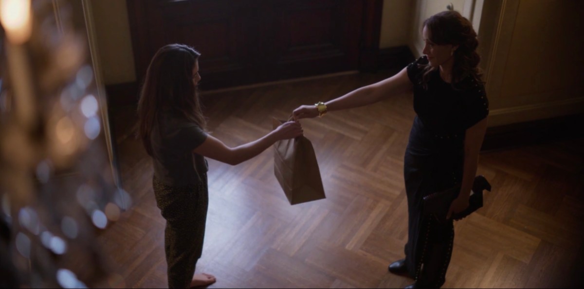 bette handing a bag to dani