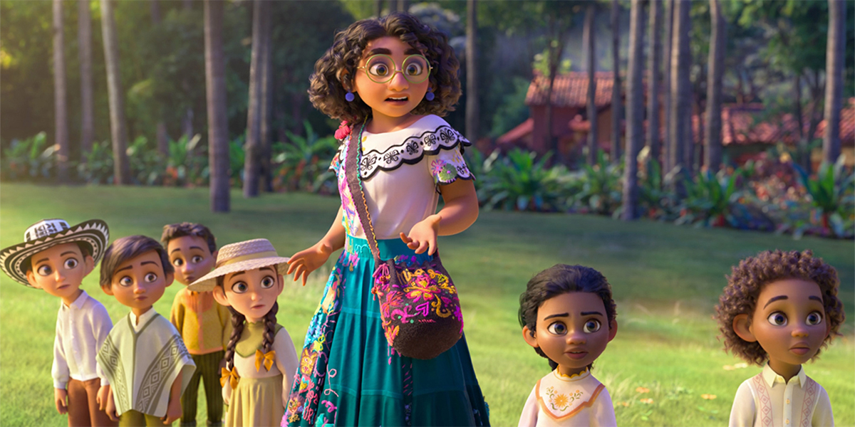 A screenshot of Disney's Ecnanto, with Stephanie Beatriz's Maribel in a white shirt and teal skirt in the grass of an enchanted village surrounded by little kids