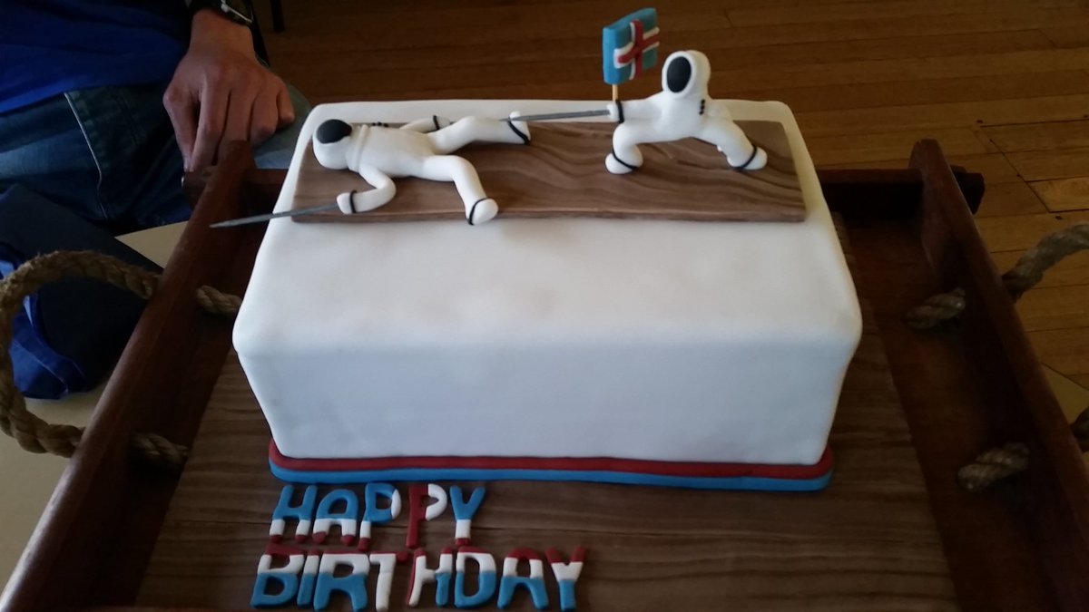 a cake decorated with a fencer knocking out another fencer