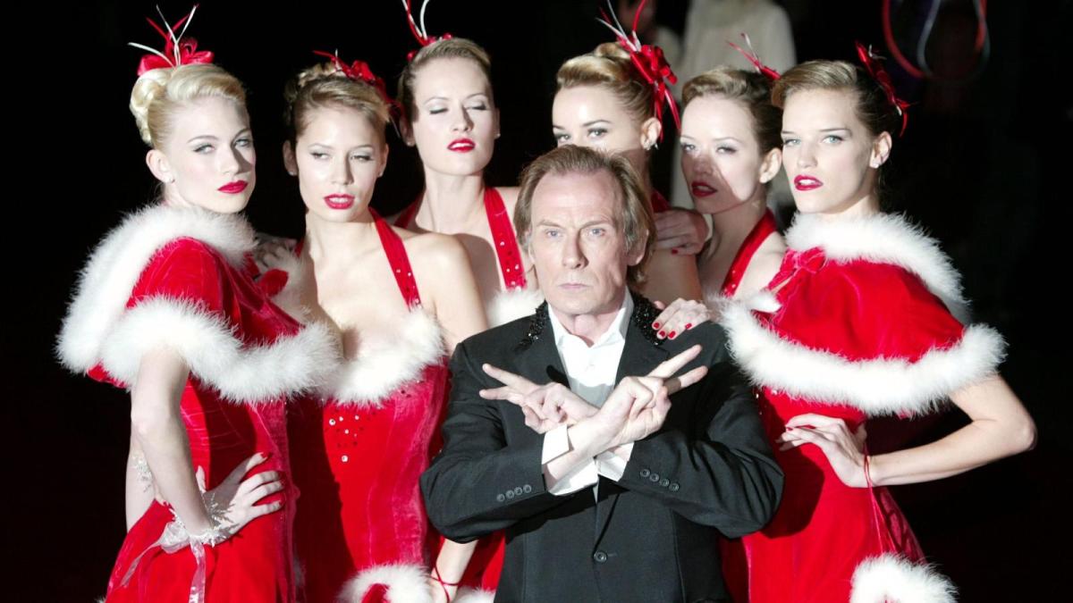 still from "Love Actually" with a bunch of girls in sexy Santa outfits