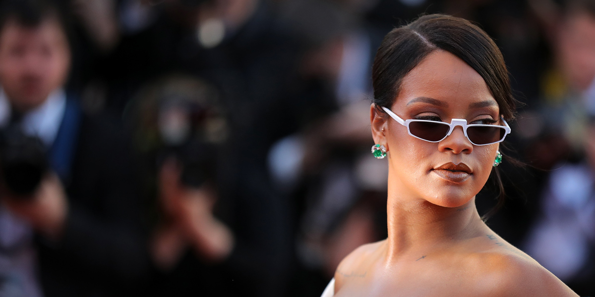 Rihanna stares over the rim of her sunglasses, her face is unimpressed