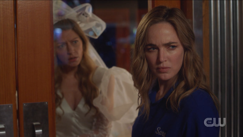 Legends of Tomorrow Episode 611: Avalance, Ava and Sara, look toward the baddies, wearing the wedding dress and bowling shirt respectively.