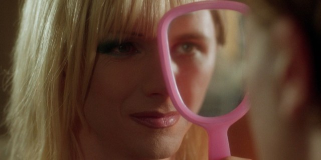 John Cameron Mitchell as Hedwig looks at Michael Pitt as Tommy Gnosis. Tommy holds up a pink mirror covering half of Hedwig's face so his face appears to complete hers.