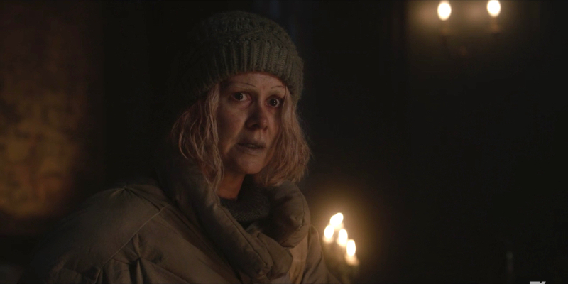 Sarah Paulson as TB Karen wearing an old beanie and big coat looks scared.