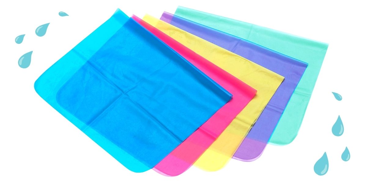 Five dental dams in different colors (blue, red, yellow, purple, and green) are against a white background. Water droplets appear in the upper left and lower right corners of the image.